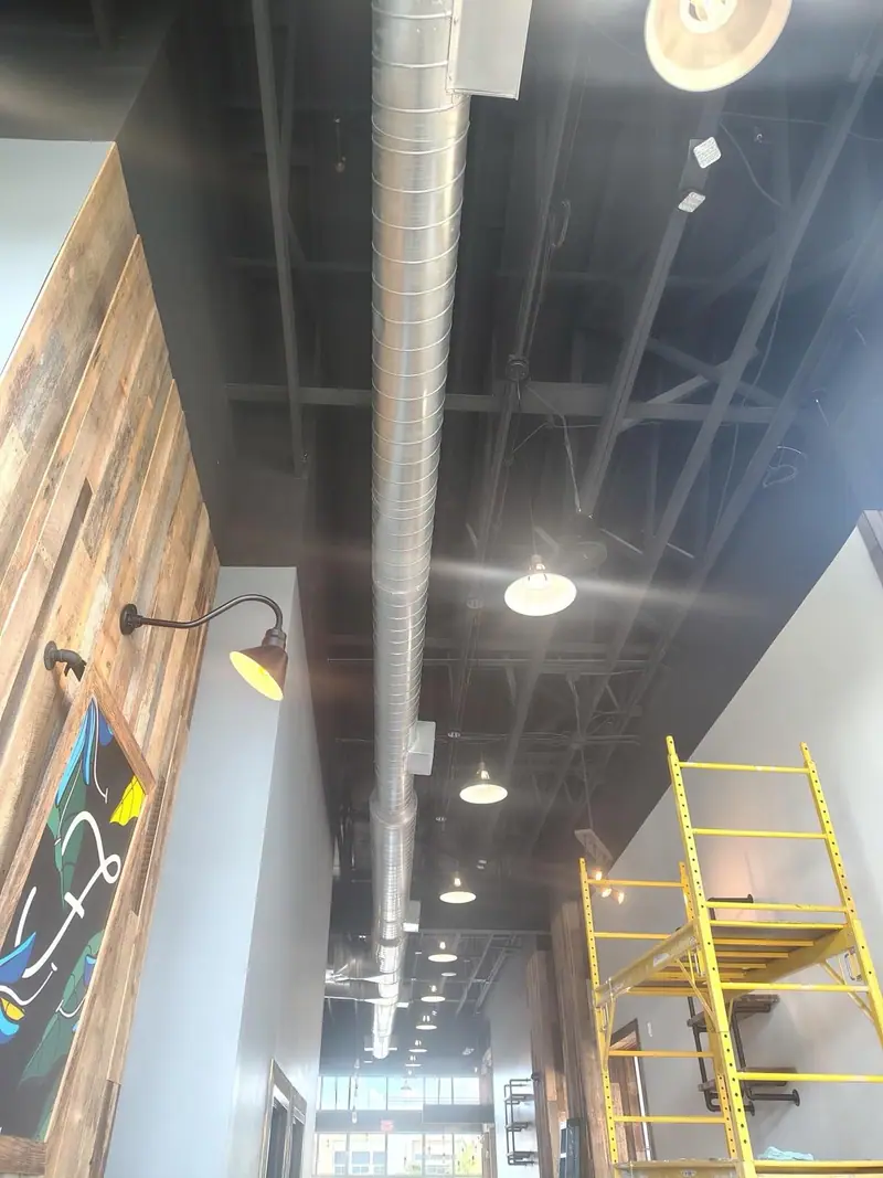 Ductwork installed overhead in an interior build-out with scaffolding
