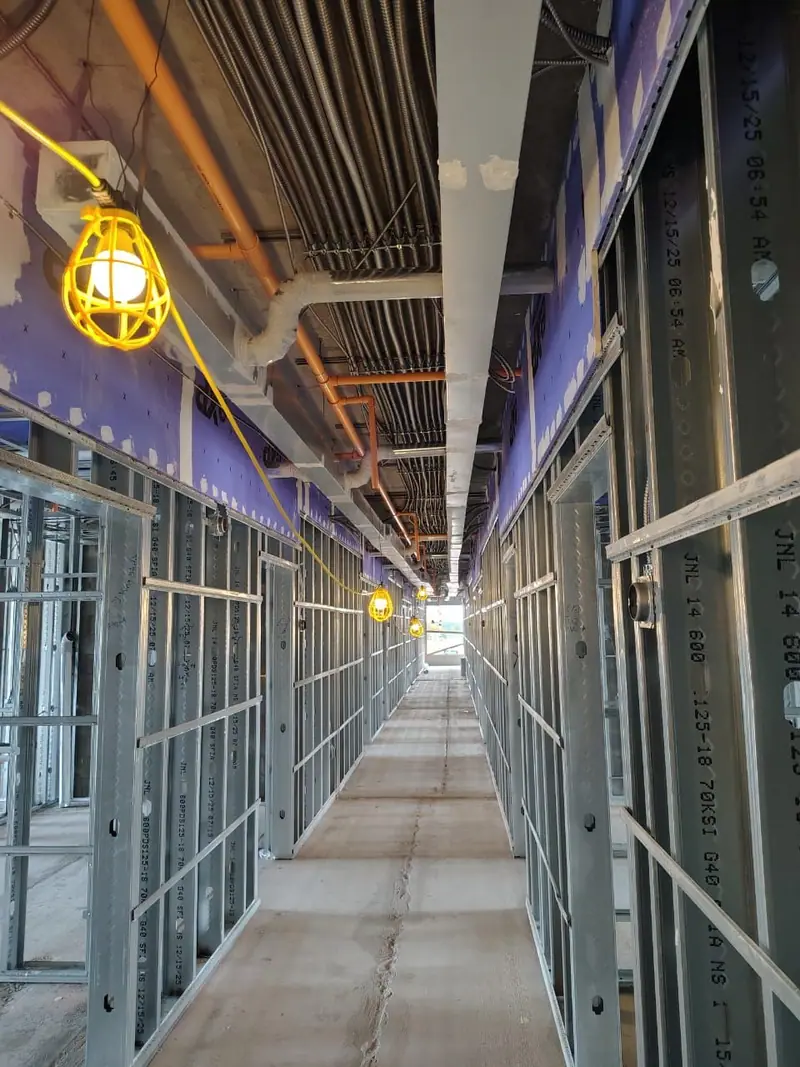 Long corridor of metal framing with mechanical piping and duct overhead