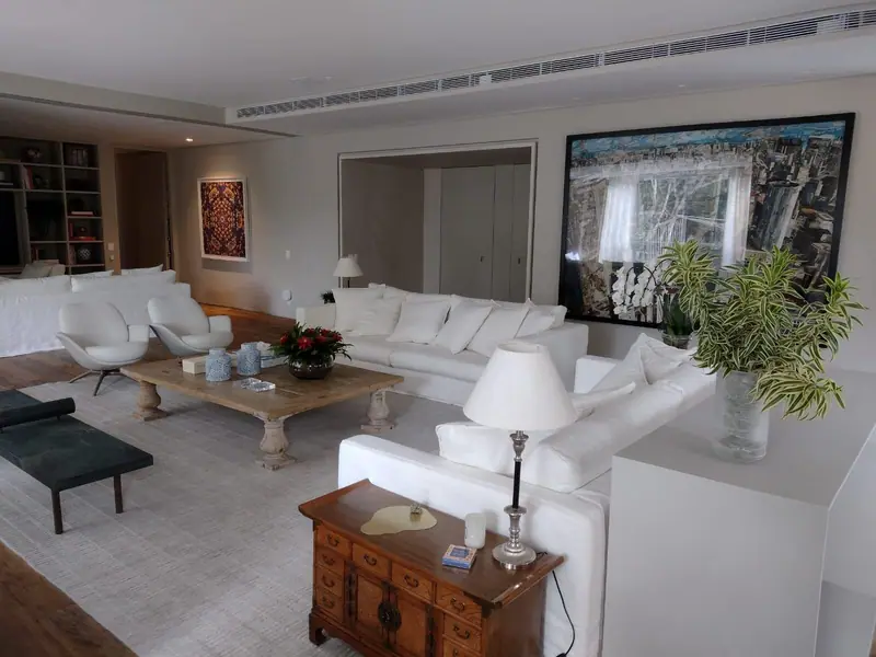 Long linear diffuser set into the ceiling above a large living room with white sofas and framed artwork